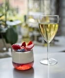 Un vidrio del vino blanco y de un postre del panakota imagen de archivo Un vidrio del vino blanco y de un postre del panakota imagen de archivo