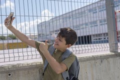 Un étudiant se reposant en dehors d'une école et jouant avec un téléphone portable Photos libres de droits Un étudiant se reposant en dehors d'une école et jouant avec un téléphone portable Photos libres de droits