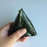 Un ‘Onikiri’ en una mano de la señora Alimento japonés tradicional foto de archivo libre de regalías Un ‘Onikiri’ en una mano de la señora Alimento japonés tradicional foto de archivo libre de regalías