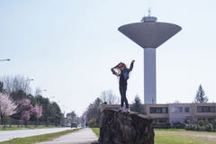 Una bambina sta stando vicino alla torre di acqua Il tempo di primavera? ? aumentato foglie, sfondo naturale Giorno pieno di sole fotografie stock libere da diritti Una bambina sta stando vicino alla torre di acqua Il tempo di primavera? ? aumentato foglie, sfondo naturale Giorno pieno di sole fotografie stock libere da diritti