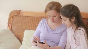 Una bella madre e la sua piccola conversazione della figlia bene, la madre tiene una compressa ed insegna a sua figlia stock footage Una bella madre e la sua piccola conversazione della figlia bene, la madre tiene una compressa ed insegna a sua figlia stock footage
