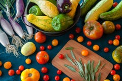 Una bontà di prodotti freschi compreso le cipolle, il pomodoro, la zucca, il pepe, la salvia ed il cetriolo su un fondo colorato immagine stock Una bontà di prodotti freschi compreso le cipolle, il pomodoro, la zucca, il pepe, la salvia ed il cetriolo su un fondo colorato immagine stock