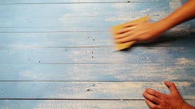 Una cantidad acelerada de una persona que pule al tablero de madera con papel de lija para que él parezca más viejo Una cantidad acelerada de una persona que pule al tablero de madera con papel de lija para que él parezca más viejo