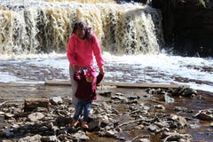 Una chica joven camina con su niño en la cascada fotografía de archivo libre de regalías Una chica joven camina con su niño en la cascada fotografía de archivo libre de regalías