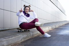 Una chica joven escucha la música y canta en un monopatín imágenes de archivo libres de regalías Una chica joven escucha la música y canta en un monopatín imágenes de archivo libres de regalías