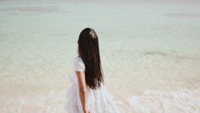 Una colegiala filipina encantadora en un vestido blanco está caminando a lo largo de una playa arenosa blanca Disfrutar del paisa almacen de metraje de vídeo Una colegiala filipina encantadora en un vestido blanco está caminando a lo largo de una playa arenosa blanca Disfrutar del paisa almacen de metraje de vídeo
