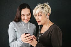 Una donna anziana e una ragazza ascoltano insieme musica Comunicazione fra la gente delle generazioni differenti Immagini Stock Una donna anziana e una ragazza ascoltano insieme musica Comunicazione fra la gente delle generazioni differenti Immagini Stock