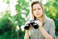 Una donna bionda con il binocolo nero resta all'aperto fotografia stock Una donna bionda con il binocolo nero resta all'aperto fotografia stock