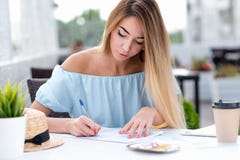 Una donna di affari, di estate in un ristorante del caffè, riempie un contratto scritto, mette una firma sul contratto, rendente immagini stock libere da diritti Una donna di affari, di estate in un ristorante del caffè, riempie un contratto scritto, mette una firma sul contratto, rendente immagini stock libere da diritti