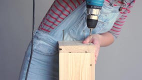Una donna fa un lavoro non femminile - perfora un pozzo con un cacciavite in una scatola di legno archivi video Una donna fa un lavoro non femminile - perfora un pozzo con un cacciavite in una scatola di legno archivi video