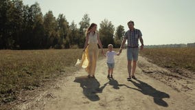 Una famiglia di tre felice che cammina insieme nella campagna stock footage Una famiglia di tre felice che cammina insieme nella campagna stock footage