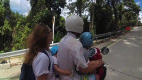 Una familia feliz monta una moto en las zonas tropicales almacen de video Una familia feliz monta una moto en las zonas tropicales almacen de video