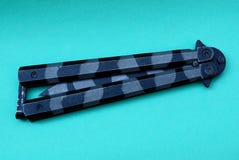 Una farfalla d'acciaio chiusa macchiata del coltello si trova su una tavola verde immagini stock libere da diritti Una farfalla d'acciaio chiusa macchiata del coltello si trova su una tavola verde immagini stock libere da diritti