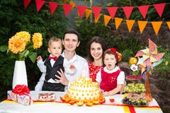 Una gente di famiglia di quattro sta sedendosi ad una tavola festiva con un dolce ed i regali Cattiva festa noiosa del ` s dei ba fotografia stock libera da diritti Una gente di famiglia di quattro sta sedendosi ad una tavola festiva con un dolce ed i regali Cattiva festa noiosa del ` s dei ba fotografia stock libera da diritti