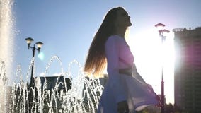 Una giovane bella ragazza sta filando vicino ad una fontana in una città di estate HD, 1920x1080 Movimento lento video d archivio Una giovane bella ragazza sta filando vicino ad una fontana in una città di estate HD, 1920x1080 Movimento lento video d archivio