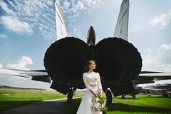 Una giovane bella sposa castana sta stando dietro un æreo a reazione immagini stock libere da diritti Una giovane bella sposa castana sta stando dietro un æreo a reazione immagini stock libere da diritti