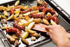Una grande padella con gli alimenti grassi: salsiccie, patate in un modo rustico Mano e spatola di legno fotografie stock libere da diritti Una grande padella con gli alimenti grassi: salsiccie, patate in un modo rustico Mano e spatola di legno fotografie stock libere da diritti