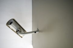 Una macchina fotografica bianca del CCTV sulla parete marrone immagine stock Una macchina fotografica bianca del CCTV sulla parete marrone immagine stock