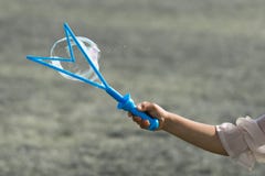 Una mano di piccola ragazza che tiene un creatore di bolla blu e che fa le bolle immagini stock Una mano di piccola ragazza che tiene un creatore di bolla blu e che fa le bolle immagini stock