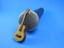Una miniatura de la guitarra acústica apoyó para arriba en un micrófono dinámico foto de archivo Una miniatura de la guitarra acústica apoyó para arriba en un micrófono dinámico foto de archivo