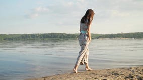 Una morenita con el pelo largo da un paseo a lo largo de la playa a lo largo de la playa en la puesta del sol metrajes Una morenita con el pelo largo da un paseo a lo largo de la playa a lo largo de la playa en la puesta del sol metrajes