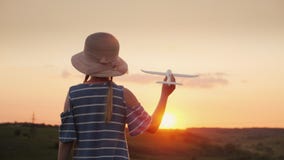 Una muchacha con las coletas y un sombrero que juega con un aeroplano de madera en la puesta del sol El sueño del viaje de larga imágenes de archivo libres de regalías Una muchacha con las coletas y un sombrero que juega con un aeroplano de madera en la puesta del sol El sueño del viaje de larga imágenes de archivo libres de regalías