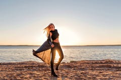 Una muchacha de un cuerpo deportivo camina en la danza y camina a lo largo de la playa arenosa en el amanecer del sol en la ropa imagenes de archivo Una muchacha de un cuerpo deportivo camina en la danza y camina a lo largo de la playa arenosa en el amanecer del sol en la ropa imagenes de archivo
