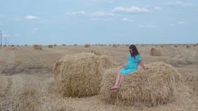Una muchacha embarazada en un vestido y un sombrero azules en un cielo azul y un campo de trigo con las gavillas de heno metrajes Una muchacha embarazada en un vestido y un sombrero azules en un cielo azul y un campo de trigo con las gavillas de heno metrajes