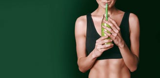 Una muchacha en los deportes negros remata los controles un tarro de los smoothies vegetales en sus manos foto de archivo libre de regalías Una muchacha en los deportes negros remata los controles un tarro de los smoothies vegetales en sus manos foto de archivo libre de regalías