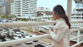 Una muchacha indonesia triste pensativa mira la situación del tráfico en un puente en Jakarta céntrica almacen de video Una muchacha indonesia triste pensativa mira la situación del tráfico en un puente en Jakarta céntrica almacen de video