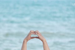 Una muestra del amor de manos femeninas en día brillante con el azul una onda azul hermosa del mar y de agua foto de archivo Una muestra del amor de manos femeninas en día brillante con el azul una onda azul hermosa del mar y de agua foto de archivo