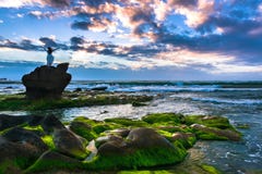 Una mujer feliz se coloca encima de Boulder en la playa y disfruta de la libertad en la salida del sol imagen de archivo Una mujer feliz se coloca encima de Boulder en la playa y disfruta de la libertad en la salida del sol imagen de archivo