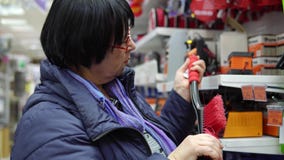 Una mujer madura elige un cepillo con el raspador en el supermercado Una mujer madura elige un cepillo con el raspador en el supermercado