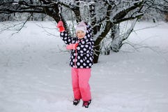 Una niña que se sienta en nieve en parque del invierno fotografía de archivo Una niña que se sienta en nieve en parque del invierno fotografía de archivo