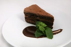 Una parte della torta di cioccolato con la salsa di cioccolato e la foglia della menta immagini stock libere da diritti Una parte della torta di cioccolato con la salsa di cioccolato e la foglia della menta immagini stock libere da diritti