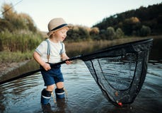 Una pequeña situación del niño pequeño en agua y llevar a cabo una red por un lago, pescando fotos de archivo Una pequeña situación del niño pequeño en agua y llevar a cabo una red por un lago, pescando fotos de archivo