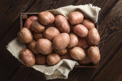 Una pila de patatas frescas en una caja de madera oscura Fondo de la lona de lino imagen de archivo Una pila de patatas frescas en una caja de madera oscura Fondo de la lona de lino imagen de archivo