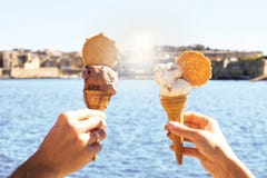 Una ragazza e un gelato della tenuta del ragazzo in cielo blu della cialda, mare blu luminoso sui precedenti nel giorno di estate Fotografia Stock Libera da Diritti Una ragazza e un gelato della tenuta del ragazzo in cielo blu della cialda, mare blu luminoso sui precedenti nel giorno di estate Fotografia Stock Libera da Diritti