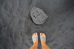 Una roccia nera della lava sulla spiaggia di sabbia nera immagini stock Una roccia nera della lava sulla spiaggia di sabbia nera immagini stock