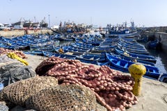 Una sección del puerto pesquero ocupado en Essaouira en Marruecos que muestra redes, los botes pequeños y los barcos rastreadores Foto de archivo Una sección del puerto pesquero ocupado en Essaouira en Marruecos que muestra redes, los botes pequeños y los barcos rastreadores Foto de archivo