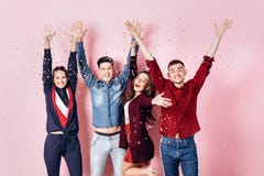 Una società allegra di due ragazze e due tipi vestiti in vestiti alla moda sono stanti e divertentesi con i coriandoli sulla a immagine stock libera da diritti Una società allegra di due ragazze e due tipi vestiti in vestiti alla moda sono stanti e divertentesi con i coriandoli sulla a immagine stock libera da diritti