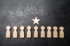 Una stella sopra una persona che sta in una fila tra altra gente Figurine di legno Il concetto di un segno di distinzione, succes immagine stock Una stella sopra una persona che sta in una fila tra altra gente Figurine di legno Il concetto di un segno di distinzione, succes immagine stock
