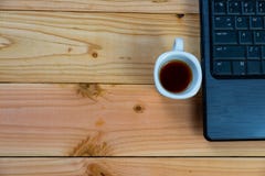 una taza de café con el labtop en el escritorio de madera foto de archivo una taza de café con el labtop en el escritorio de madera foto de archivo