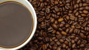 Una taza de café sólo sobre los granos de café asados fotografía de archivo Una taza de café sólo sobre los granos de café asados fotografía de archivo