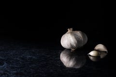 Una testa dell'aglio con i chiodi di garofano di aglio su una cucina dell'argento e del nero completa il fondo immagine stock Una testa dell'aglio con i chiodi di garofano di aglio su una cucina dell'argento e del nero completa il fondo immagine stock