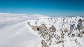 Una vista dalla cima della montagna alle scogliere coperte di neve un giorno soleggiato immagine stock Una vista dalla cima della montagna alle scogliere coperte di neve un giorno soleggiato immagine stock