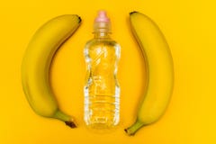 Une banane et une bouteille de l'eau sur un fond jaune photographie stock libre de droits Une banane et une bouteille de l'eau sur un fond jaune photographie stock libre de droits