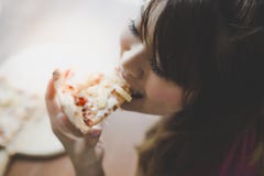 Une belle femme tient un morceau de pizza et le mange La jolie fille asiatique se sent heureuse et a plaisir à manger de la pizza photographie stock libre de droits Une belle femme tient un morceau de pizza et le mange La jolie fille asiatique se sent heureuse et a plaisir à manger de la pizza photographie stock libre de droits
