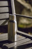 Une bouteille isolée d'acier inoxydable sur le banc dans la forêt de nuit photos stock Une bouteille isolée d'acier inoxydable sur le banc dans la forêt de nuit photos stock