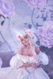 Une créature merveilleuse, une licorne de princesse dans une robe blanche de vintage Pièce légère de fond couverte de brouillard, photographie stock Une créature merveilleuse, une licorne de princesse dans une robe blanche de vintage Pièce légère de fond couverte de brouillard, photographie stock